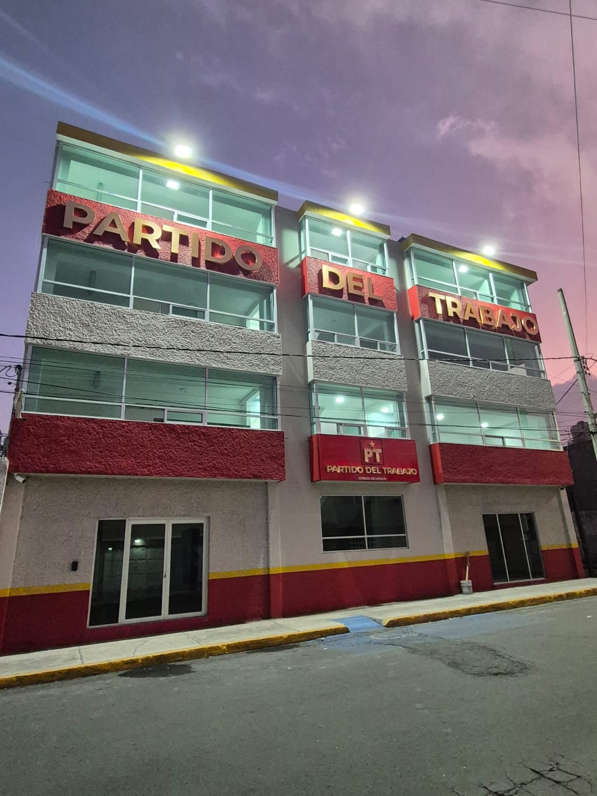 Fachada iluminada de la sede del PT Estado de México al atardecer
