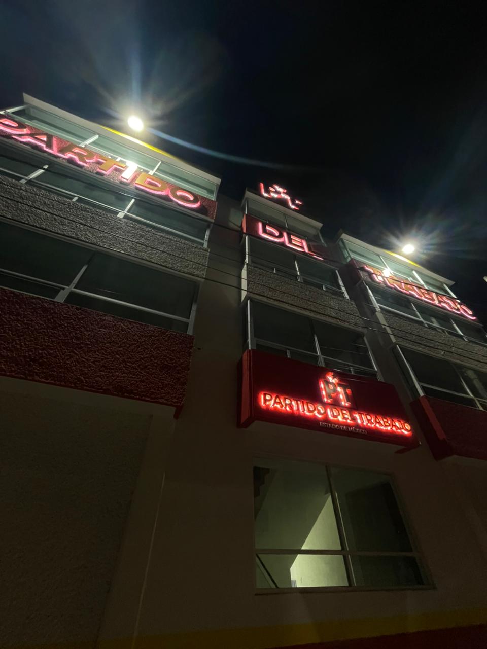 Fachada iluminada de la sede del PT Estado de México durante la noche